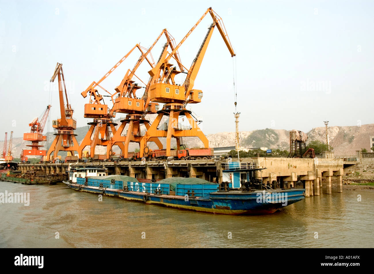 A heavy barge waiting for it's cargo of construction materials to be unloaded at a dockside on the Yangtze River, Nanjing, China Stock Photo
