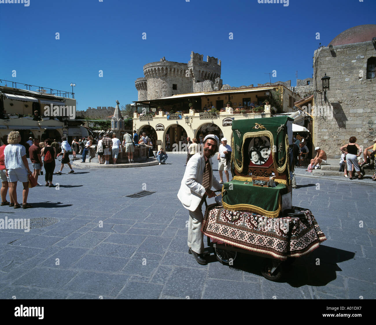 Greece, Rhodes, Dodecanese, GR-Rhodes Town, Ippokratu Square, tourists, tavernas, sidewalk cafes, Harbour Town Gate, barrel organ grinder, people, UNESCO World Heritage Site Stock Photo