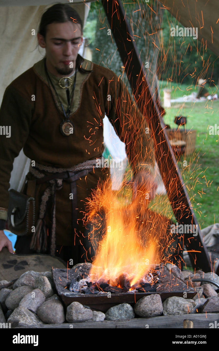 A Saxon at the reenactment of the battle of Hastings using bellows to light a fire. Stock Photo