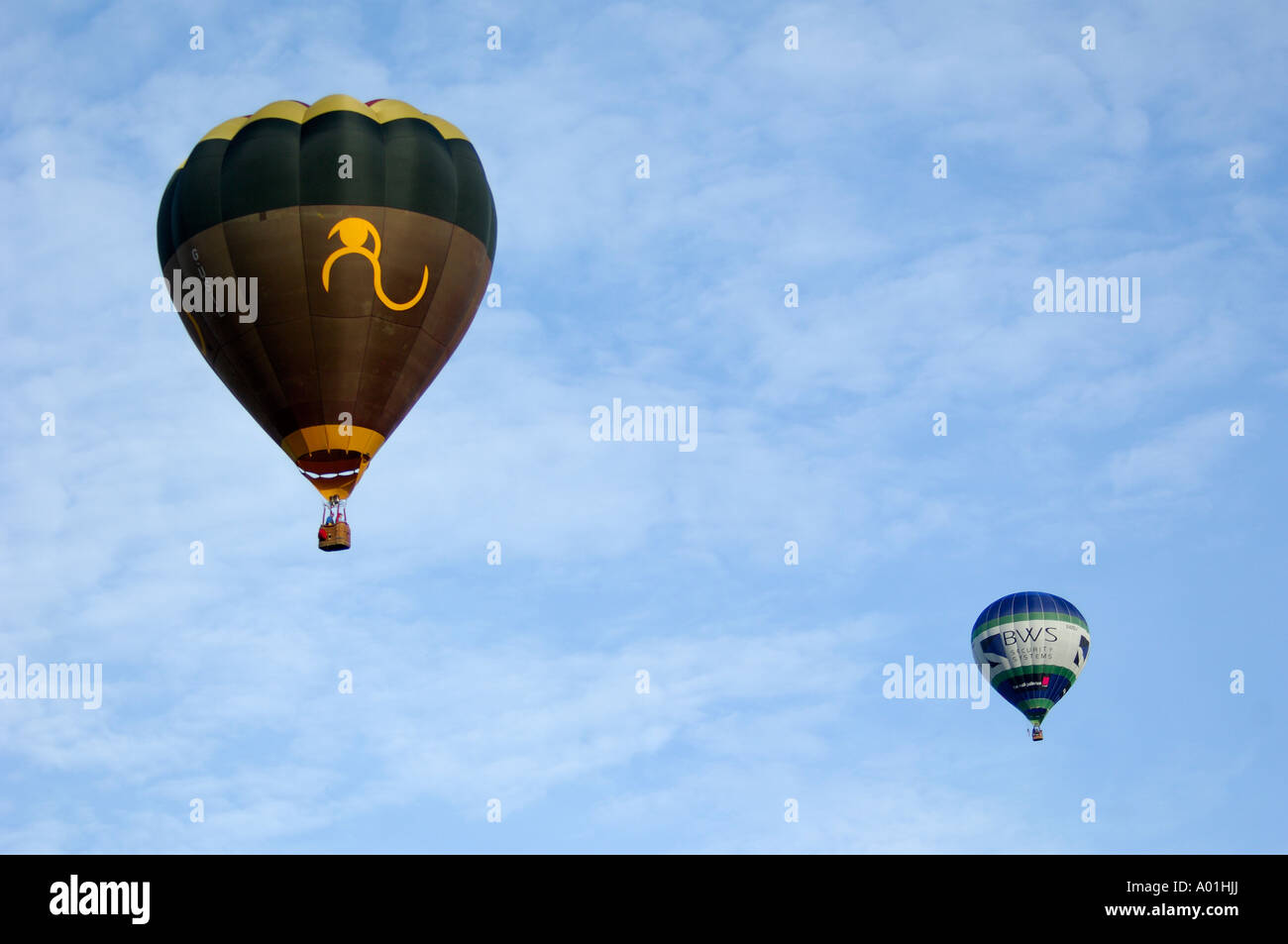 Two hot air balloons in flight against a pale blue sky Stock Photo