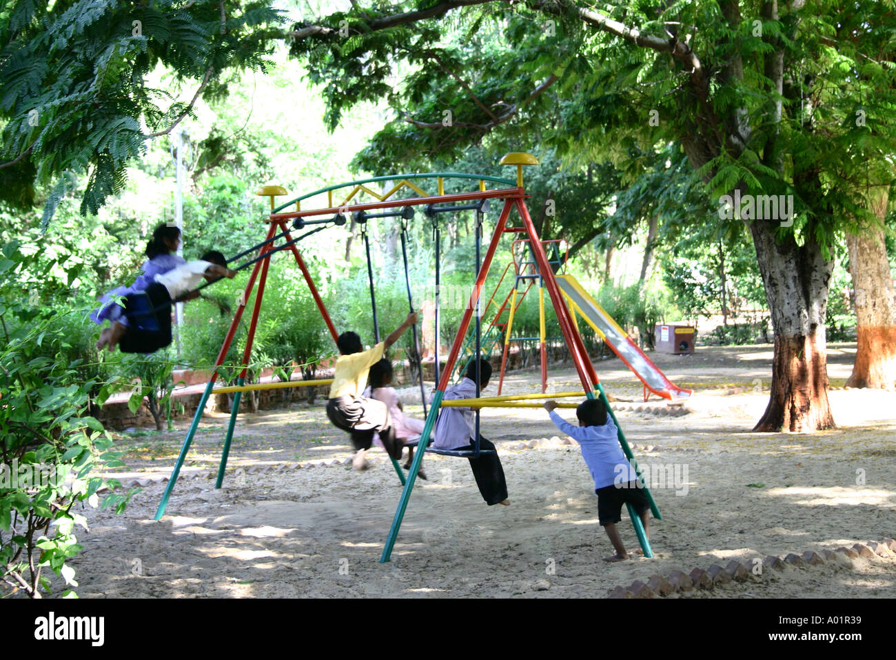 Children boys and girls playing and enjoying on swings in a park at Gandhi Dham in Gujarat India Stock Photo