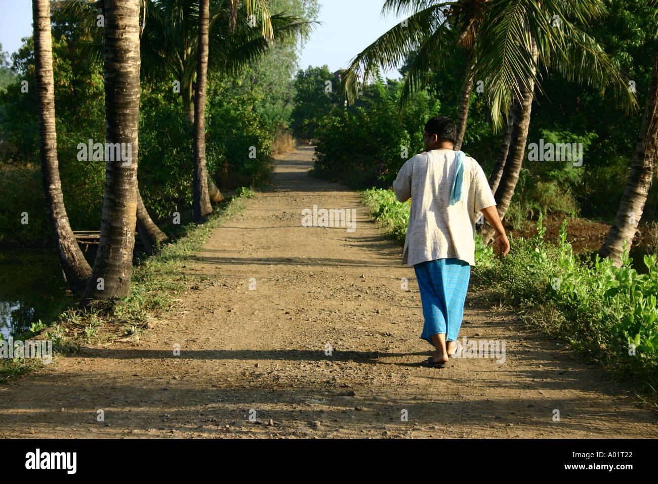 RSC048 Indian man walking on rural path wearing lungi and vest Stock Photo