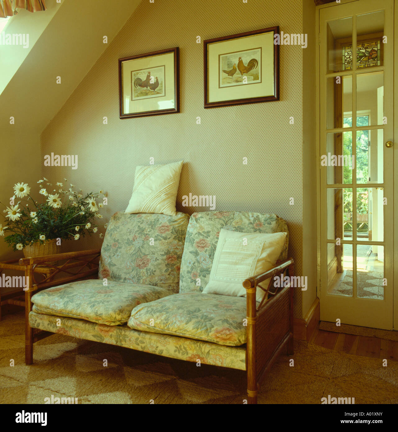 Small sofa with cushions and wooden arms beneath picture in neutral livingroom of country cottage Stock Photo