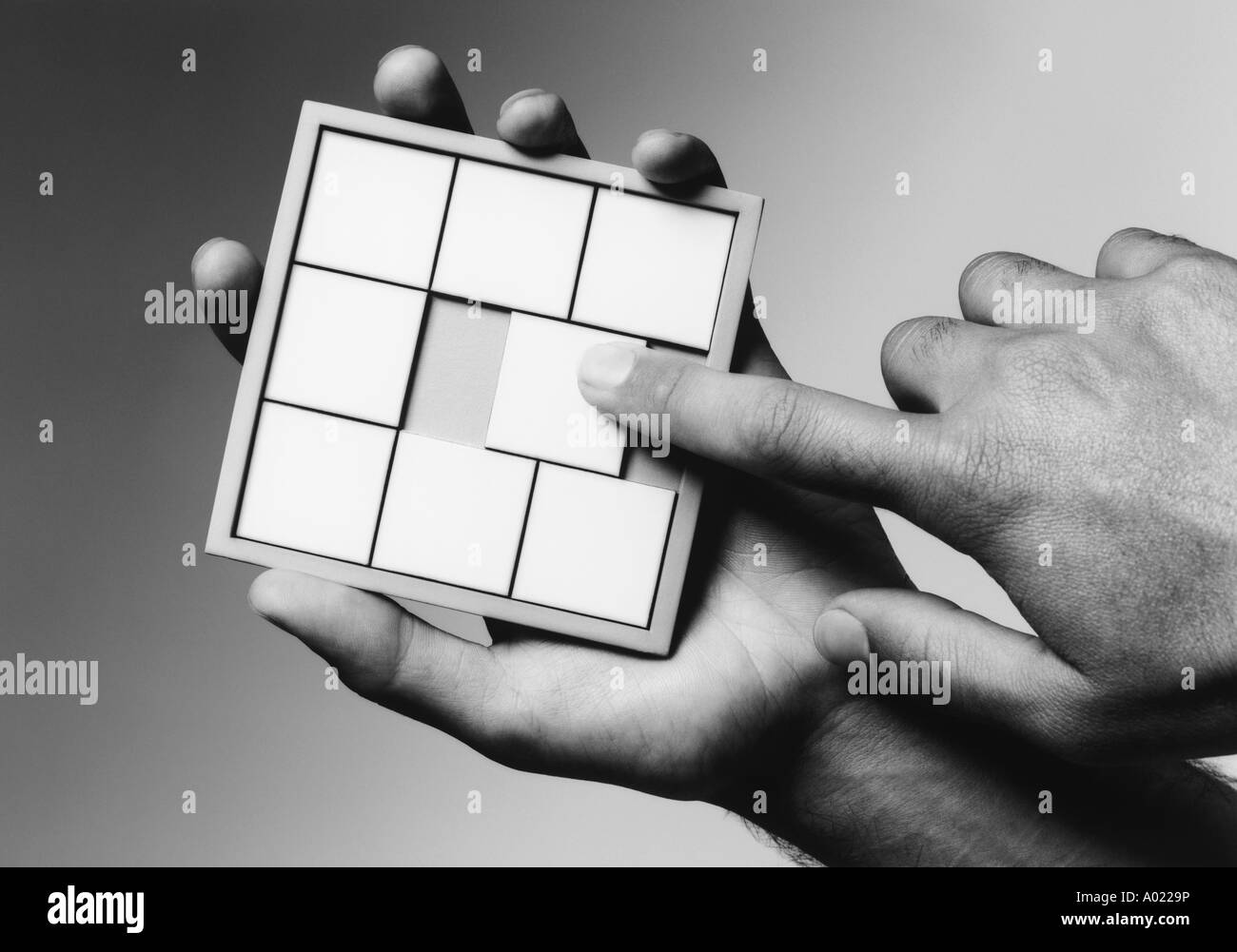 Hands holding slide puzzle, (b&w), (close-up) Stock Photo