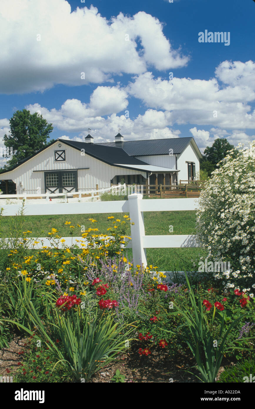 Picturesque white barn and garden with fenced paddock on small rural horse farm, Missouri USA Stock Photo