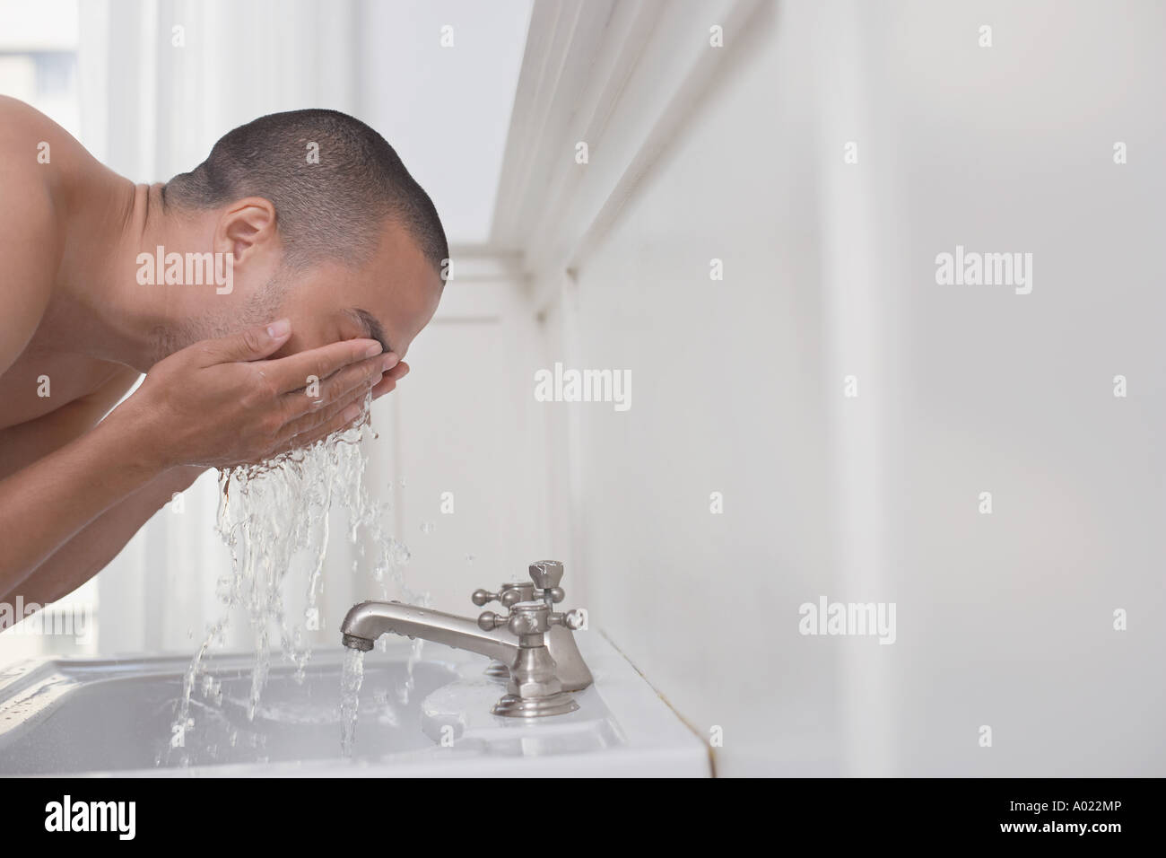 Man washing face in bathroom sink Stock Photo Alamy
