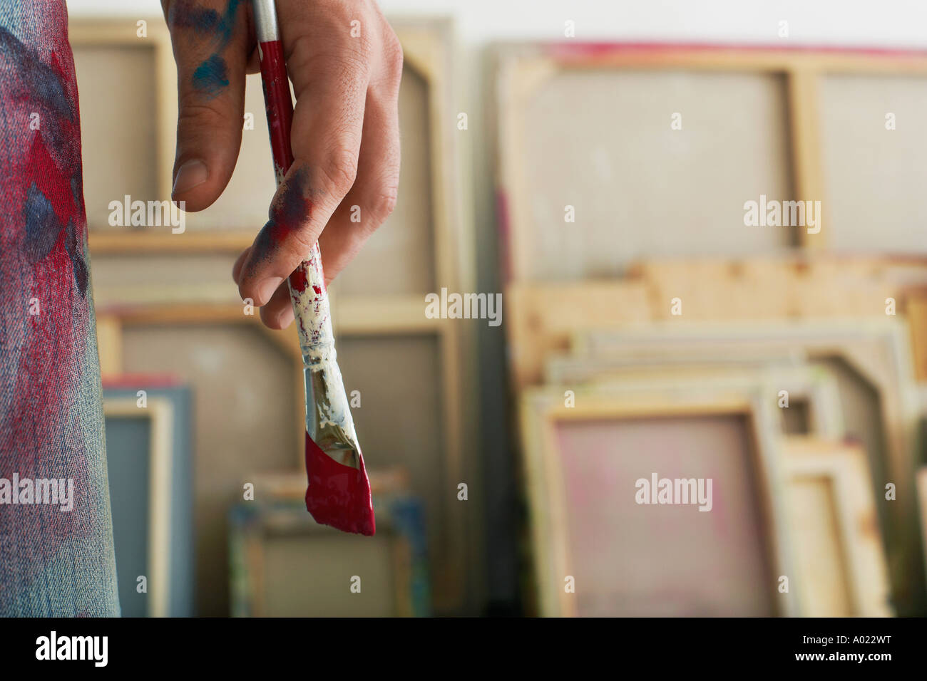 Artist holding paint brush, standing in studio, close up on hand Stock Photo
