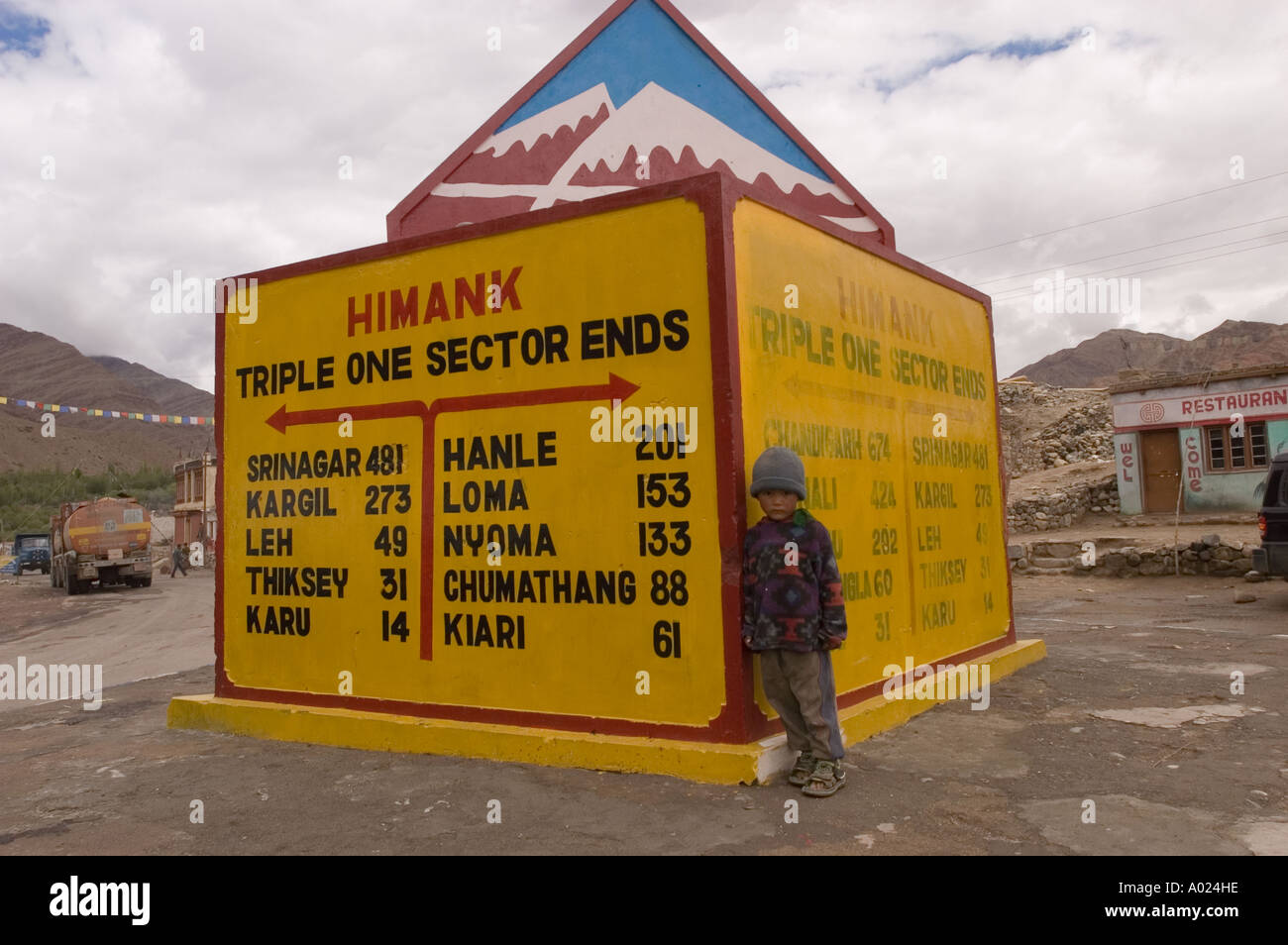Small boy standing next to road sign in Ladakh India Stock Photo