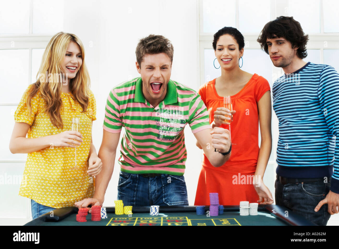 Young man with friends celebrating gambling win at roulette table Stock Photo