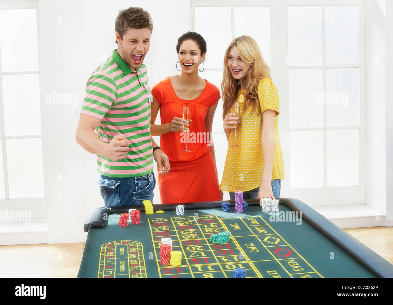 Young man with friends celebrating gambling win at roulette table Stock Photo