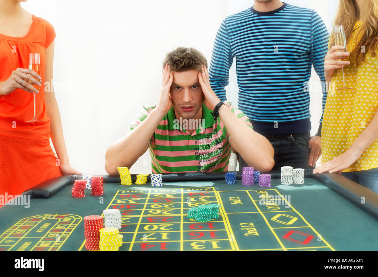Young frustrated man at roulette table with friends Stock Photo