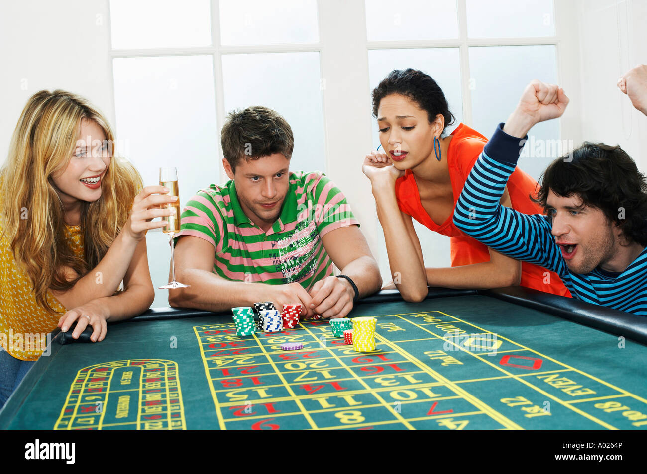Young man winning on roulette table while friends lose Stock Photo