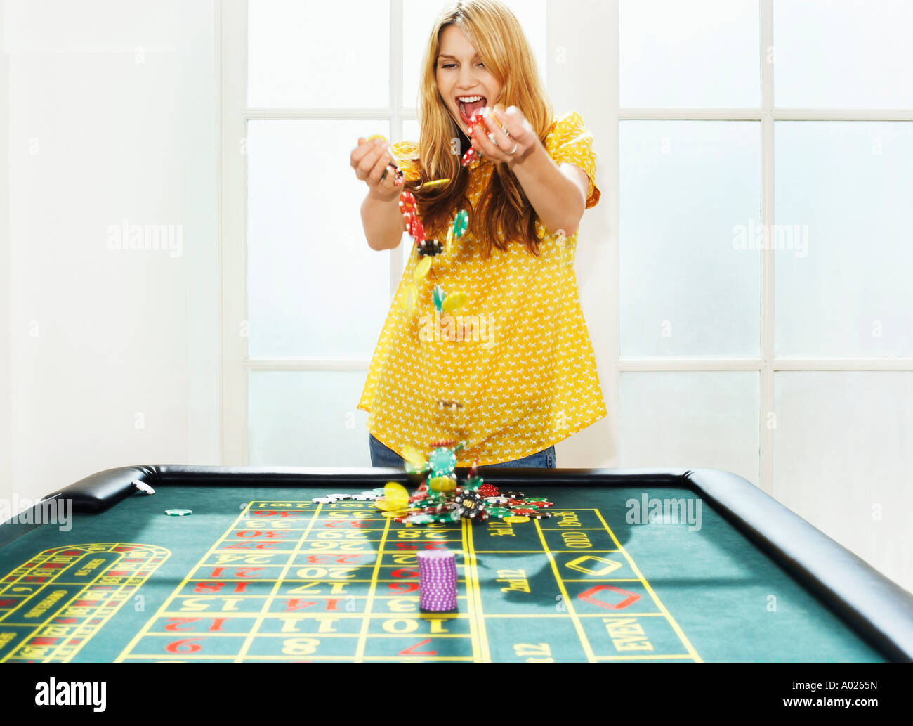 Young woman celebrating with chips on roulette table Stock Photo