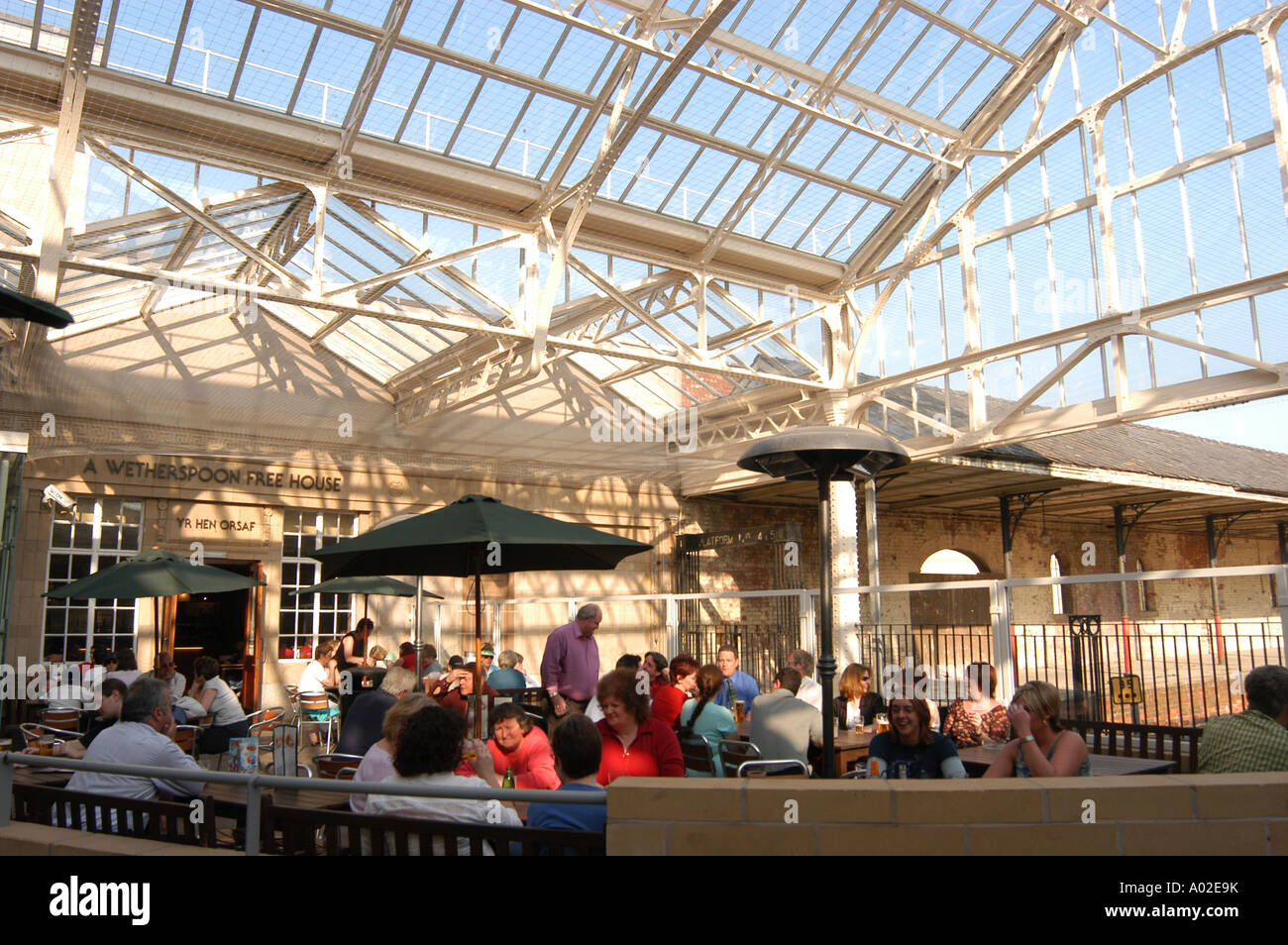 people sitting in the covered area of Wetherspoons chain pub in the converted Aberystwyth railway station building Stock Photo