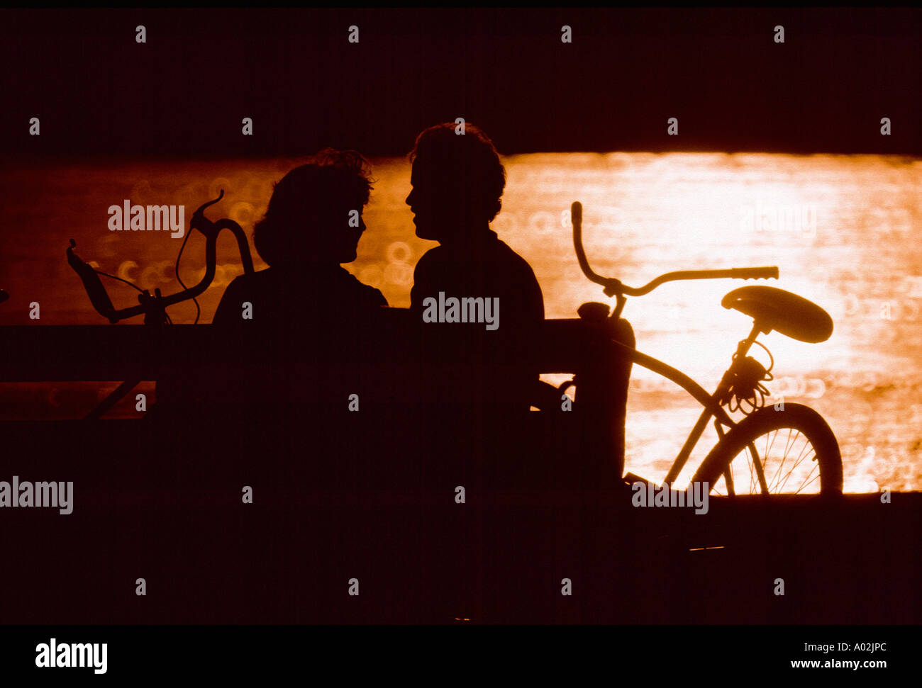Silhouette couple sitting on park bench Stock Photo