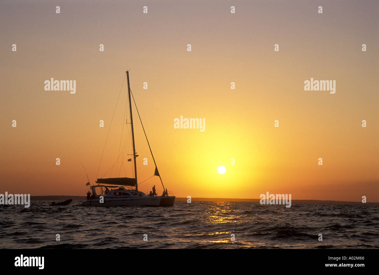 Sailing boat and the setting sun Mozambique Africa The sky is a warm red with a golden sun Stock Photo