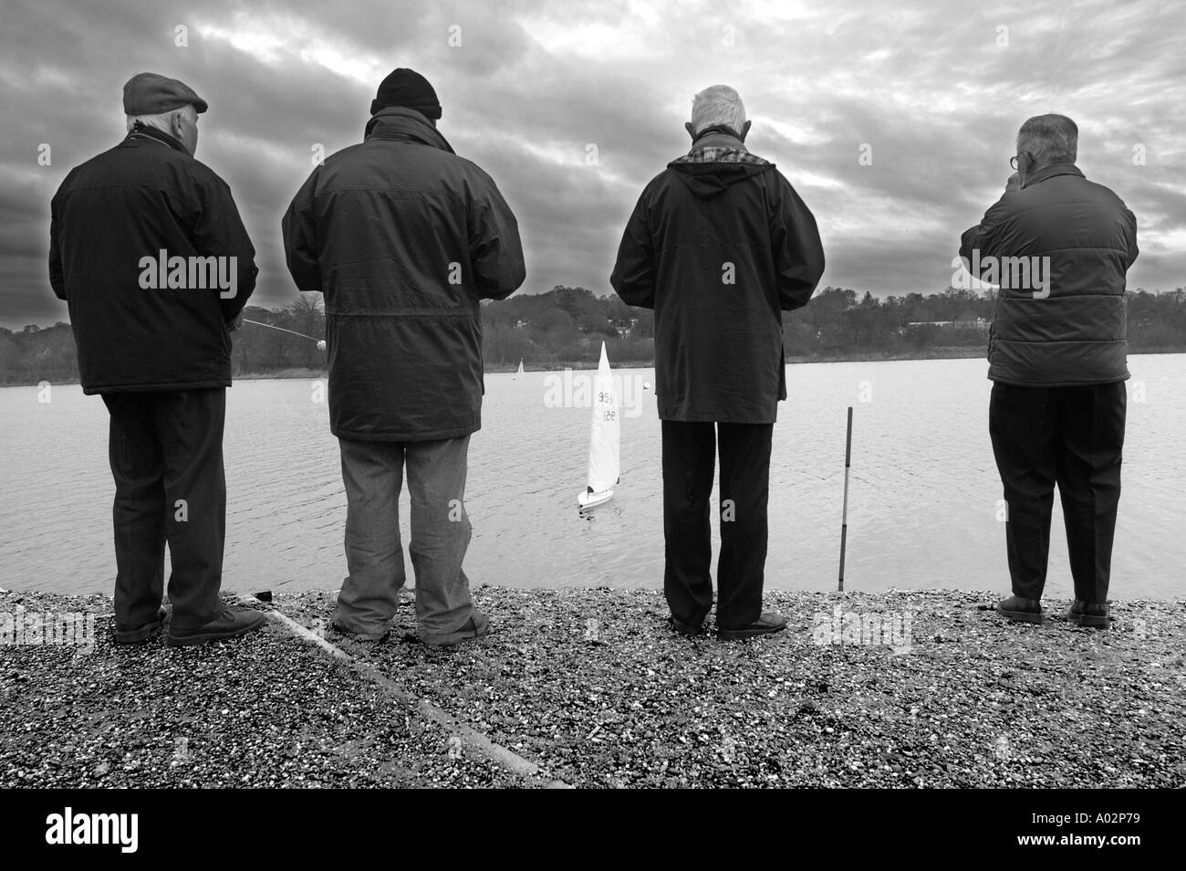 Whitlingham Country Park Norwich Norfolk Four men enjoy New Year s Day by sailing model yachts on Whitlingham Broad in Norwich Stock Photo