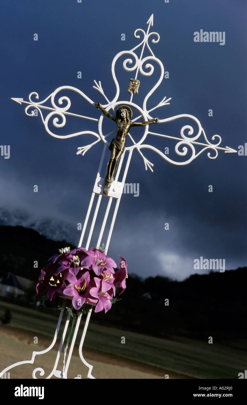 Wrought iron cross adorned with a statue of the Crucifixion against a