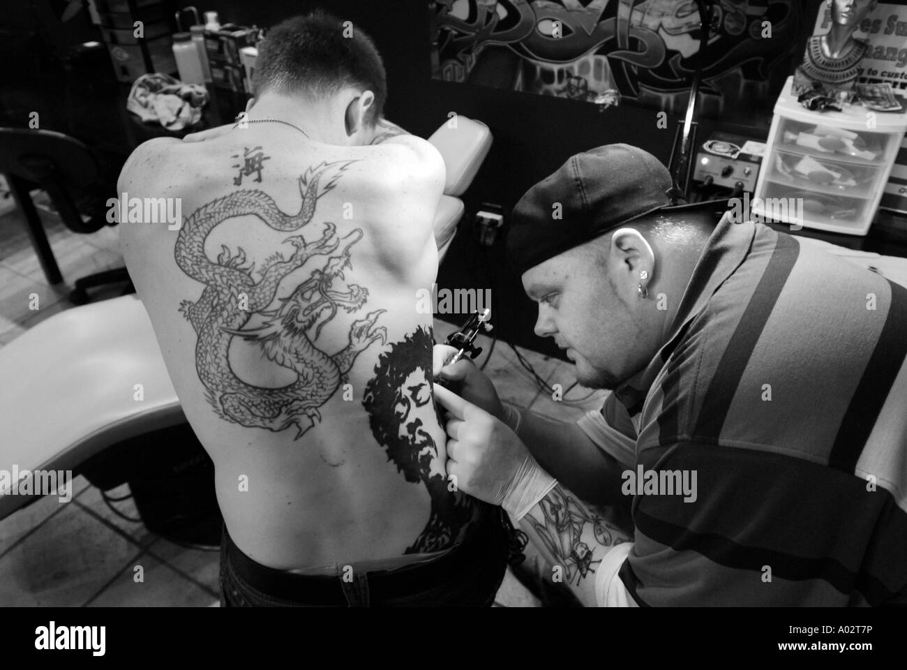 A Tattoo Artist inks a Jimi Hendrix tatoo on a man's back in black and white  Stock Photo - Alamy