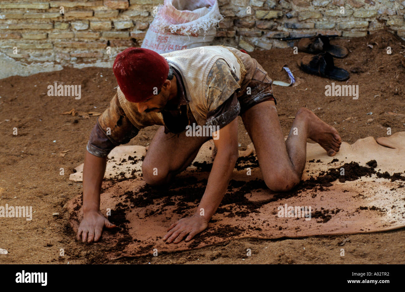 Man working on a piece of leather in a Tannery in the Medina of Fez (laterly, Fez el-bali) in the city of Fez, Morocco, Africa Stock Photo