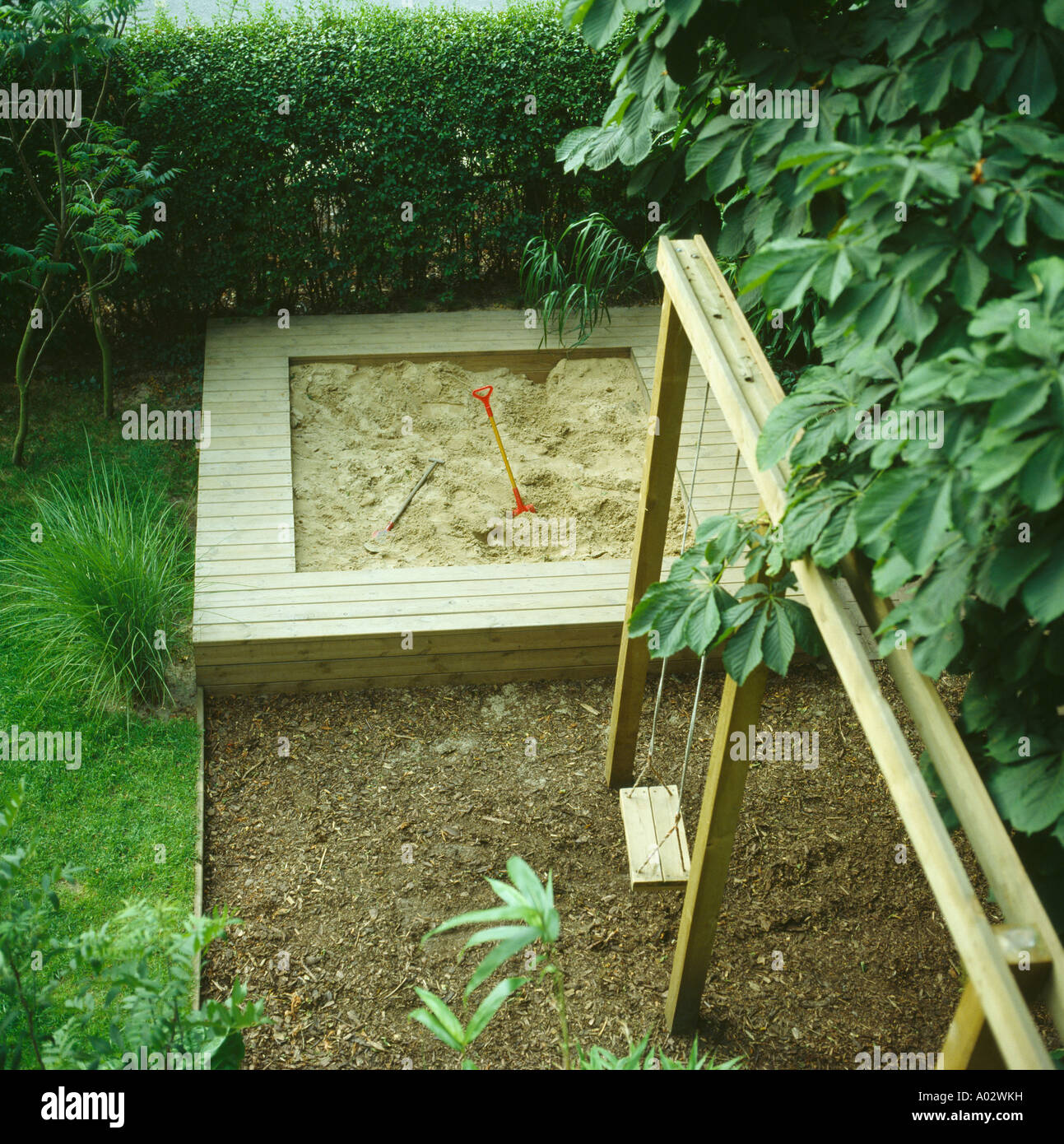 Children's sandbox and swing in town garden Stock Photo - Alamy
