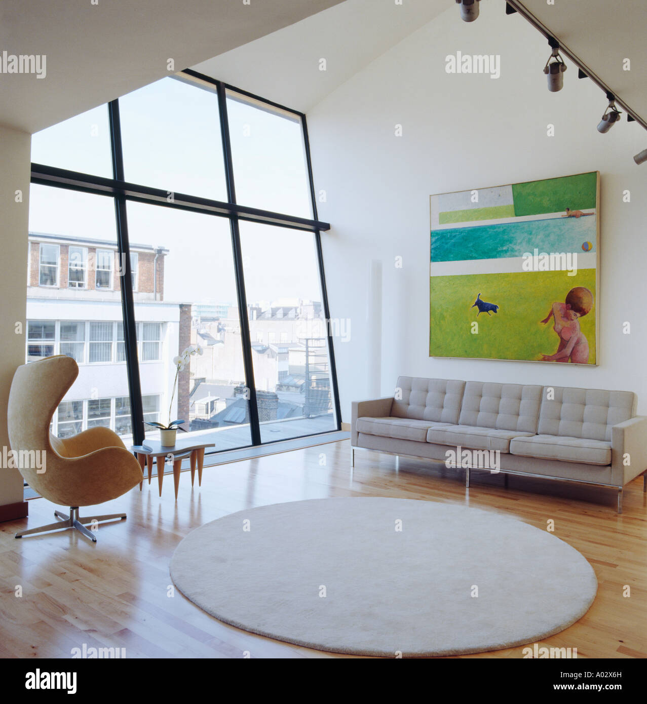 Picture above sofa and Arne Jacobsen Egg chair in modern loft conversion  livingroom with circular white rug on wood floor Stock Photo - Alamy