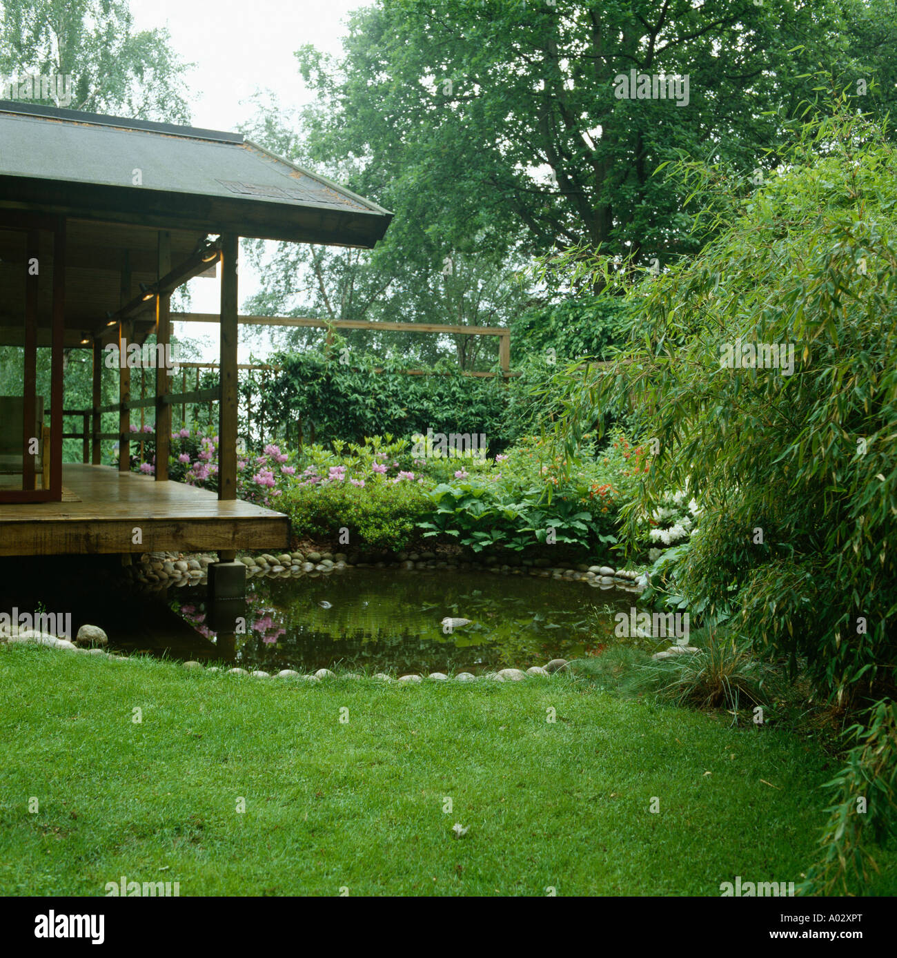 Japanese style covered veranda with round pebble edged pool Evergreen planting with bamboo Stock Photo