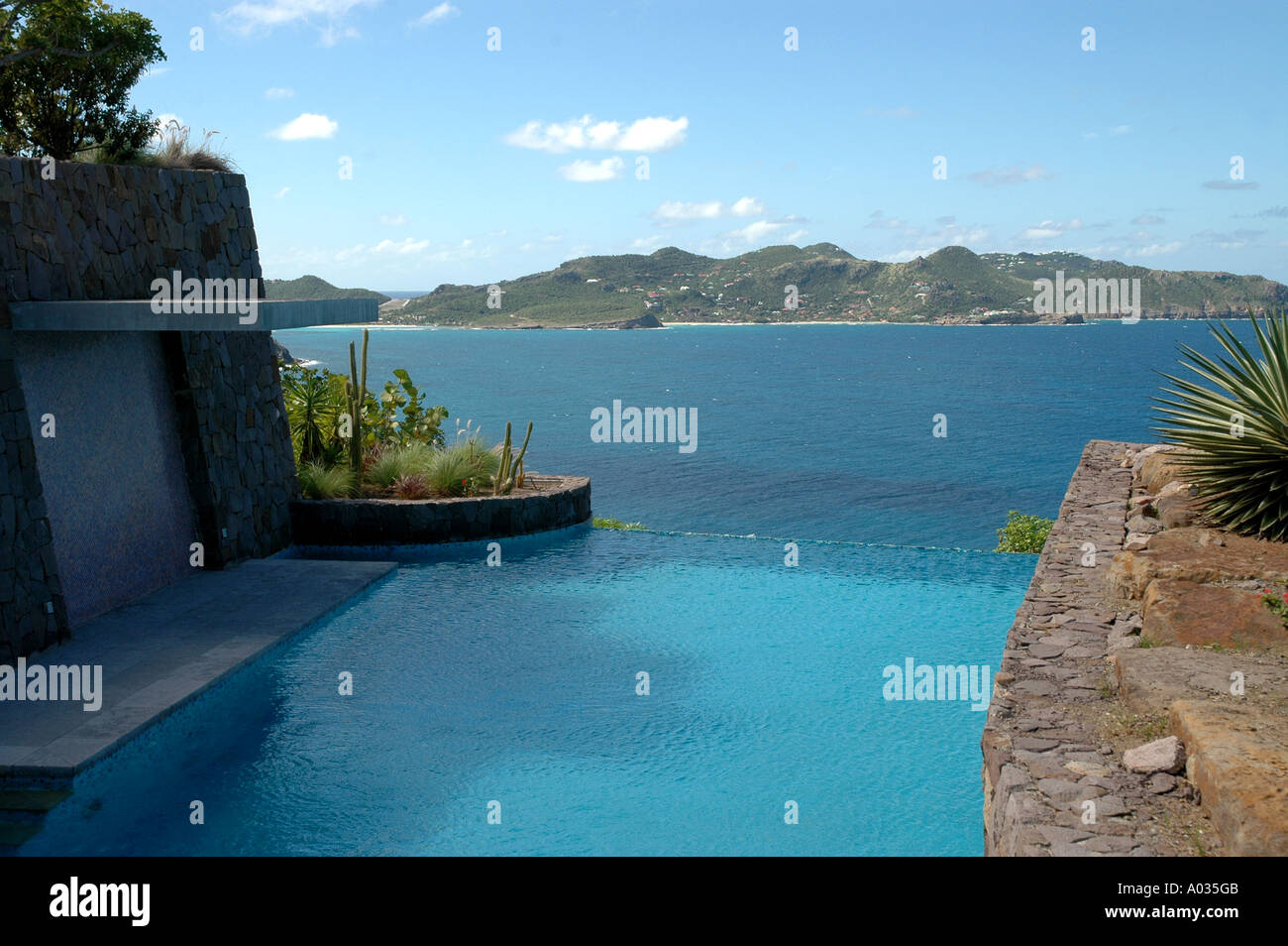 Saint Barthelmy luxury villa infinity swimming pool overlooking caribbean sea with green mountain background nobody Stock Photo