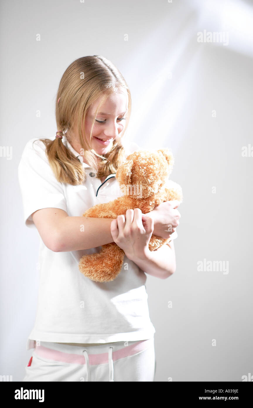 SMILING YOUNG GIRL CUDDLES HER TEDDY BEAR Stock Photo