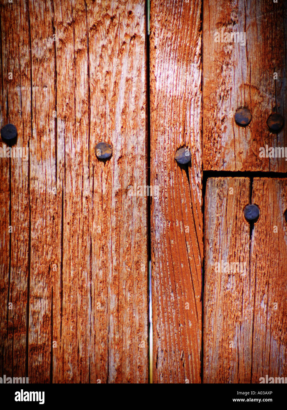Section of worn wooden fence with nails and patchwork showing slight lens vignetting Stock Photo