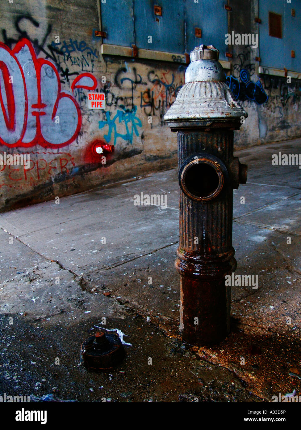Old, open fire hydrant in front of a graffiticovered wall near Harlem in New York City Stock