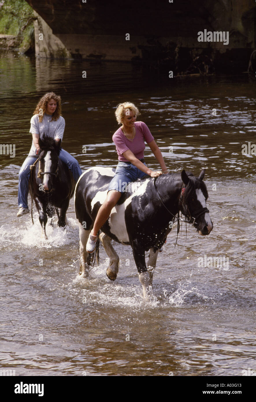 Two girls parade their horses in the river Eden at Appleby Horse Fair Stock Photo