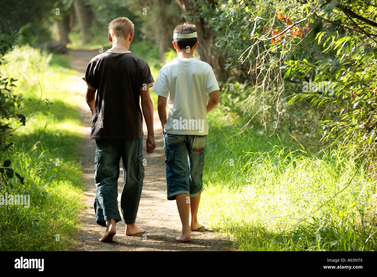 two young boys walking along a forest track in their bare feet Stock Photo  - Alamy