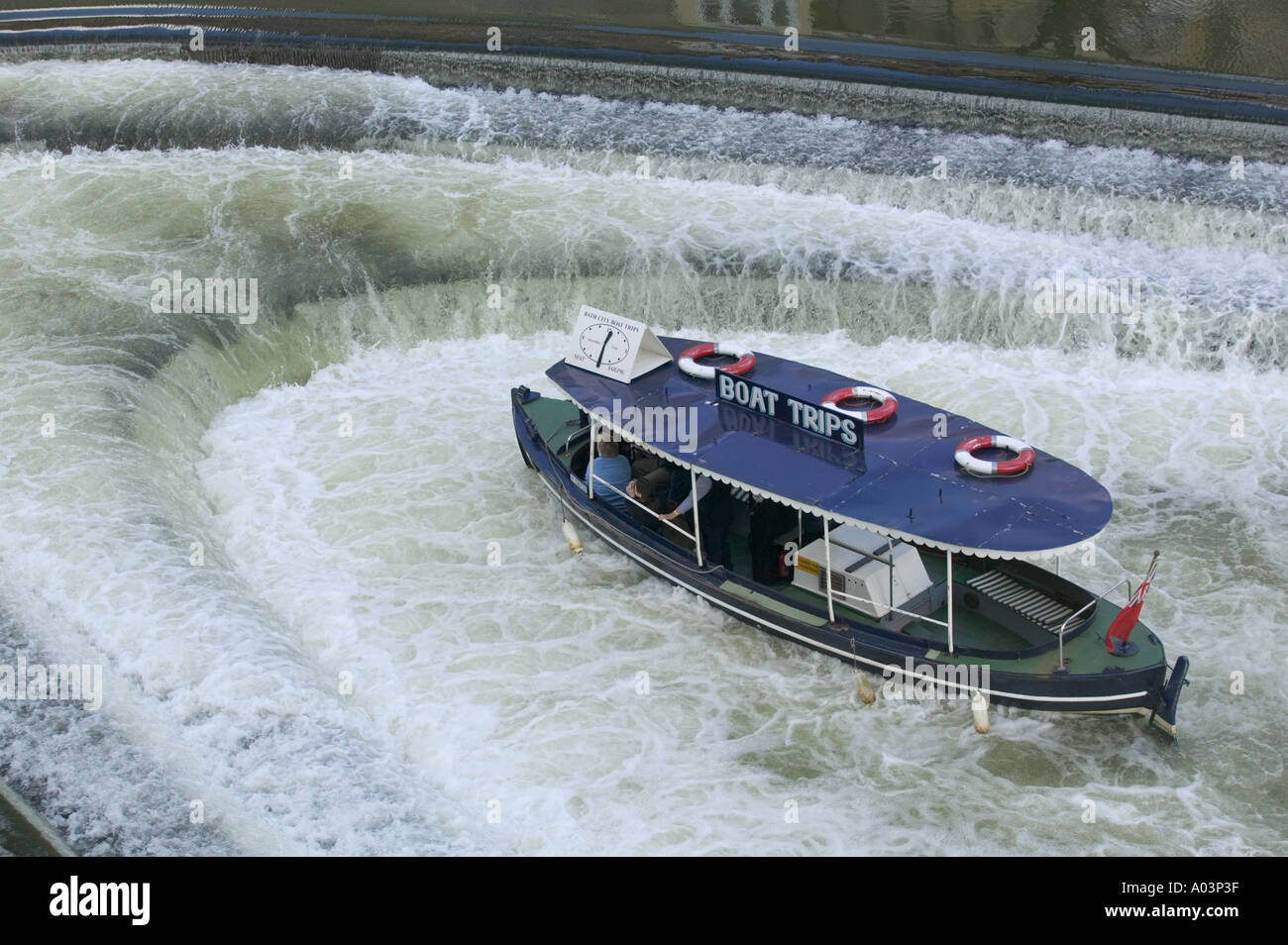 A pleasure boat in the weir beneath Pulteney Bridge, Bath, UK. Stock Photo