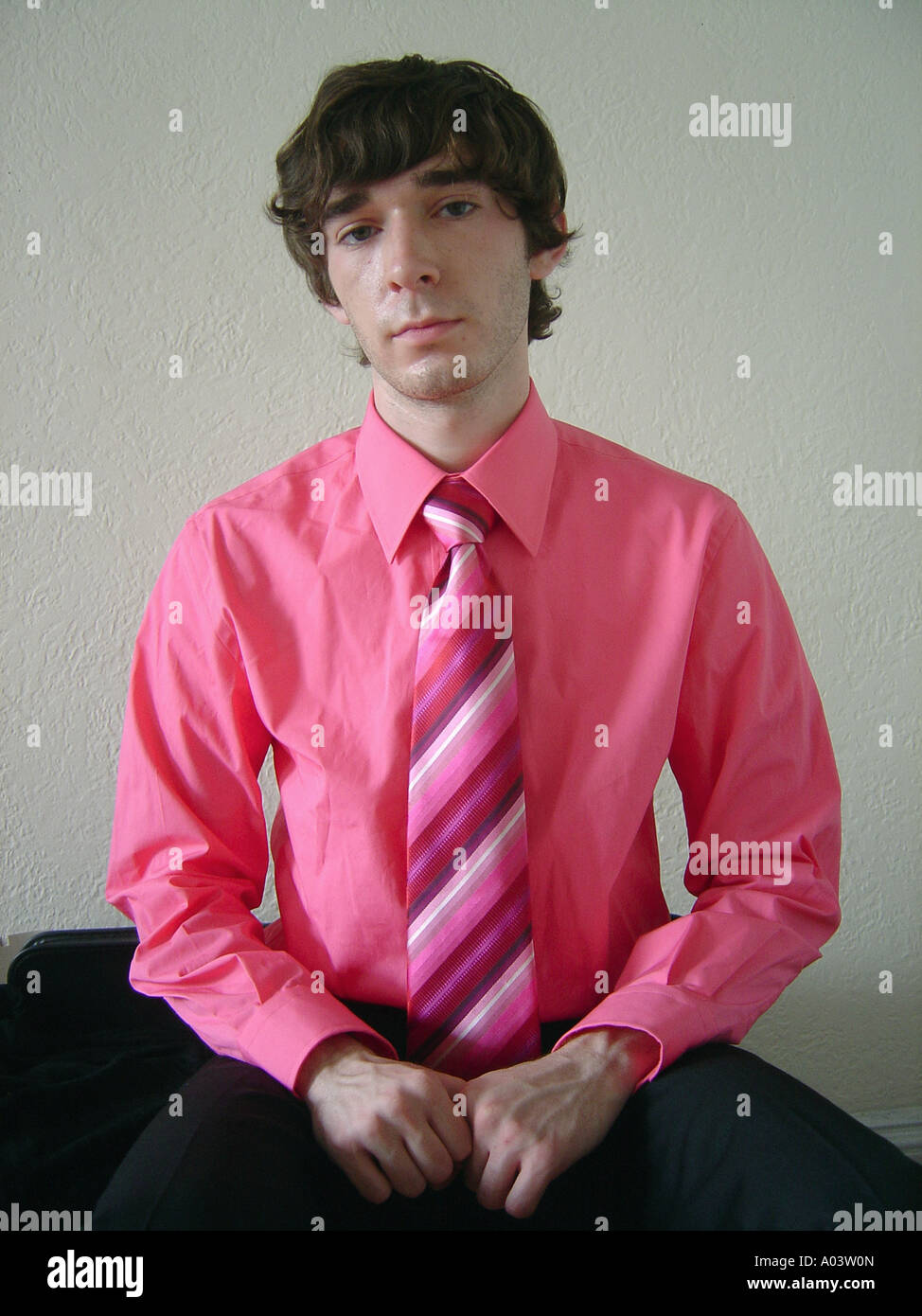 Portrait of Young Man Wearing A Pink Shirt and a Pink Striped Necktie Tie He is Looking Into Camera Lens Stock Photo