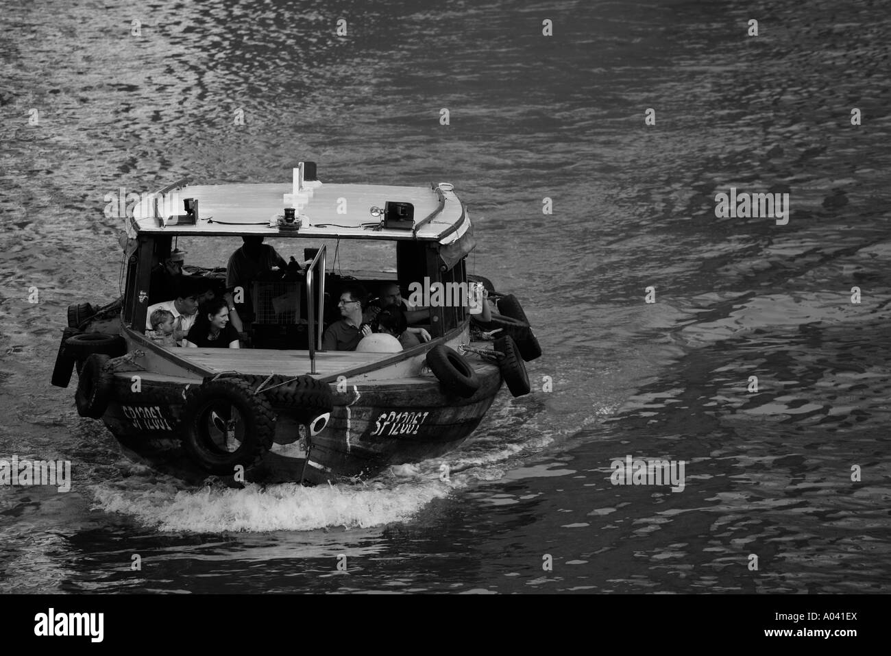 Asia Singapore Tourists bum boat motoring down Singapore River near Raffles Place at dusk Stock Photo