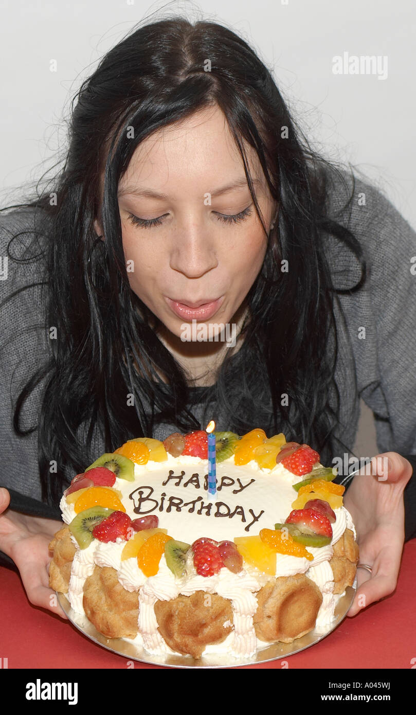 Young woman blowing out candles on a birthday cake Stock Photo Alamy