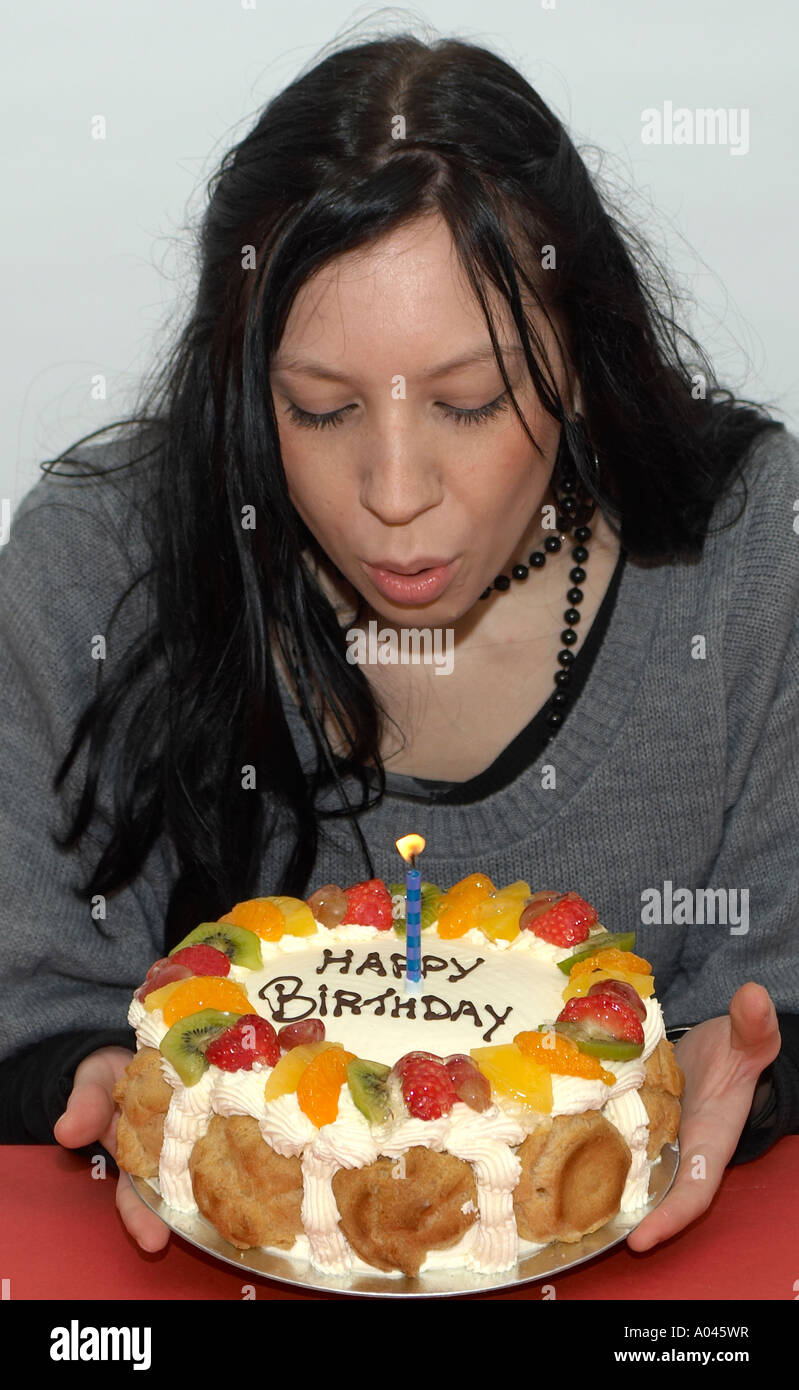 Young woman blowing out candles on a birthday cake Stock Photo Alamy