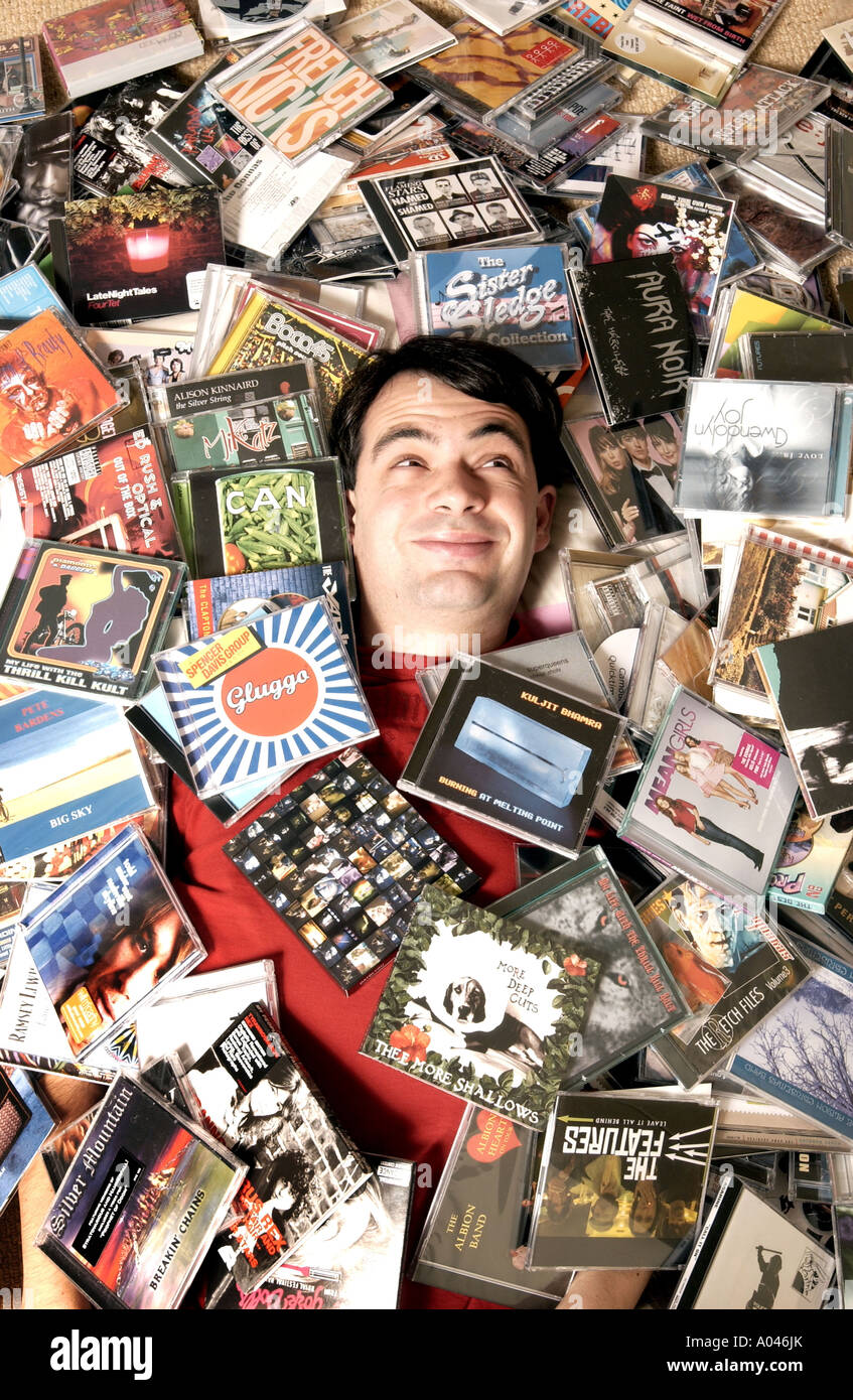 Guardian newspaper music writer Alexis Petridis buried under some of the hundreds of CD albums he has to listen to each week Stock Photo