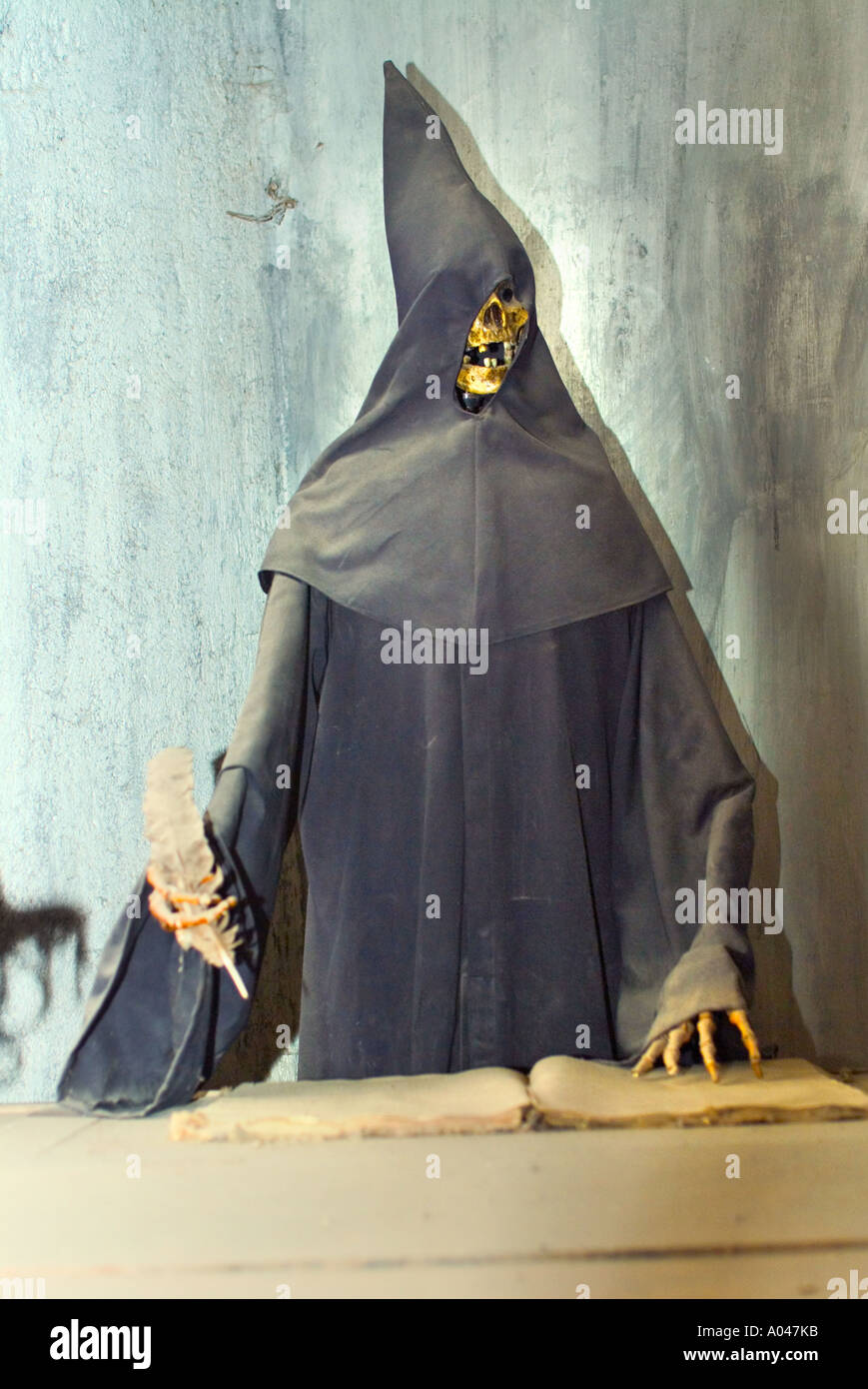 A Skeleton wearing a black robe and hood writing down names of next victims Stock Photo