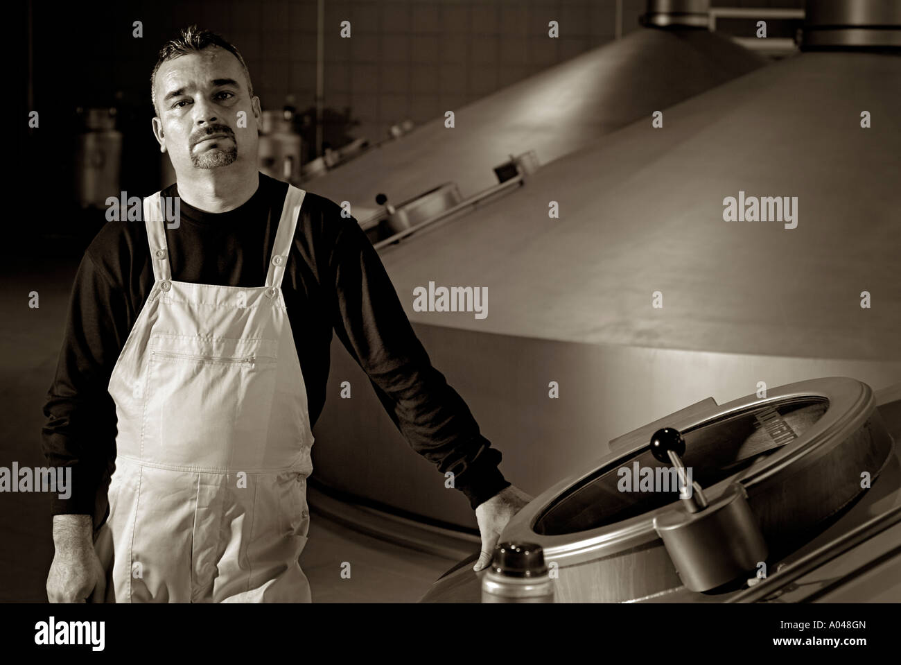 Brewery Worker Standing Next to a Large Fermentation Vat Stock Photo