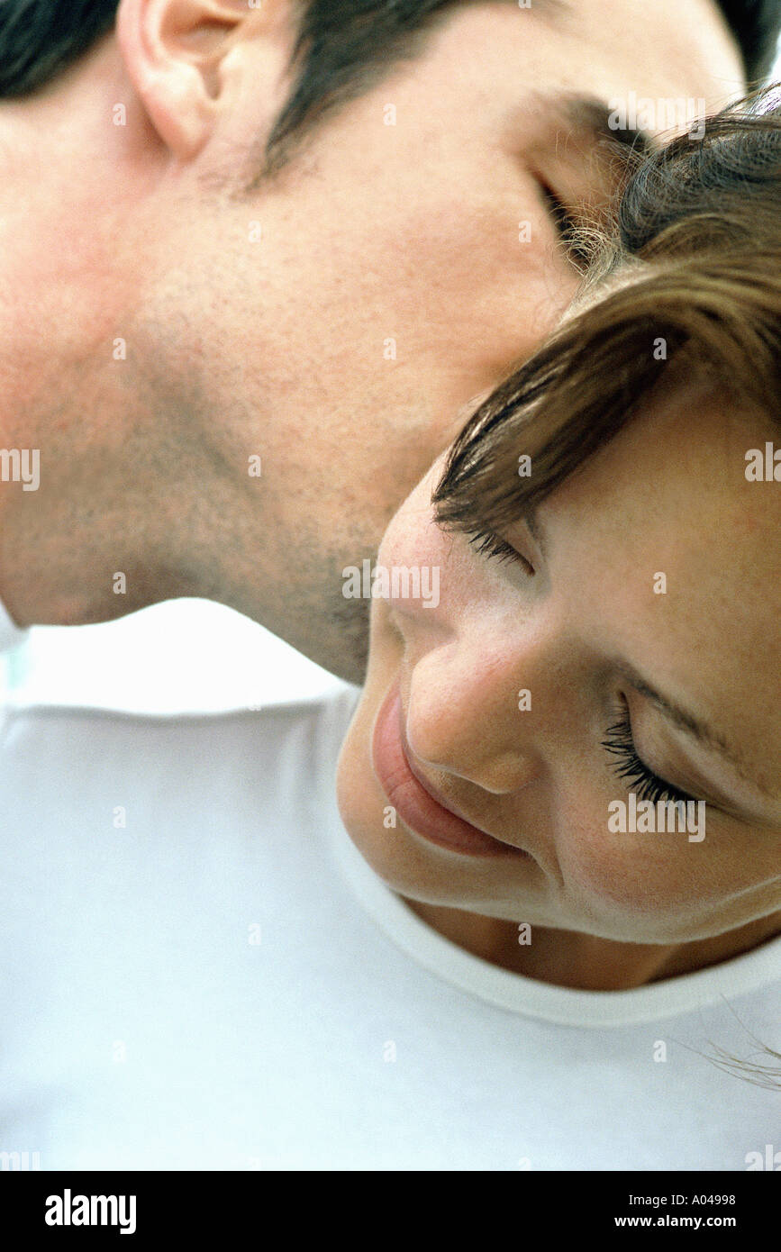 Close up portrait of a young man kissing a woman's ear Stock Photo