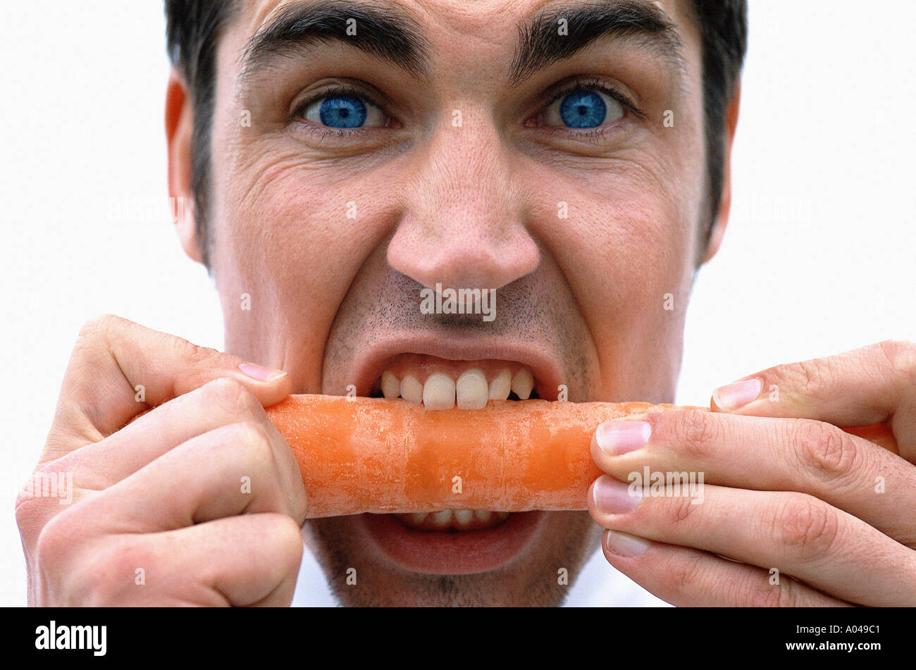 Close up portrait of young man biting into a carrot Stock Photo Alamy