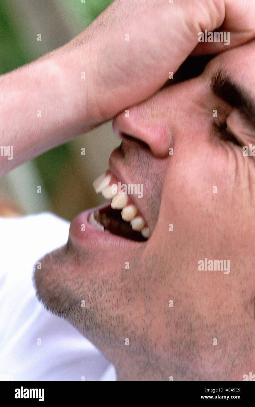 Close up portrait of young man with his hand on his face  laughing Stock Photo