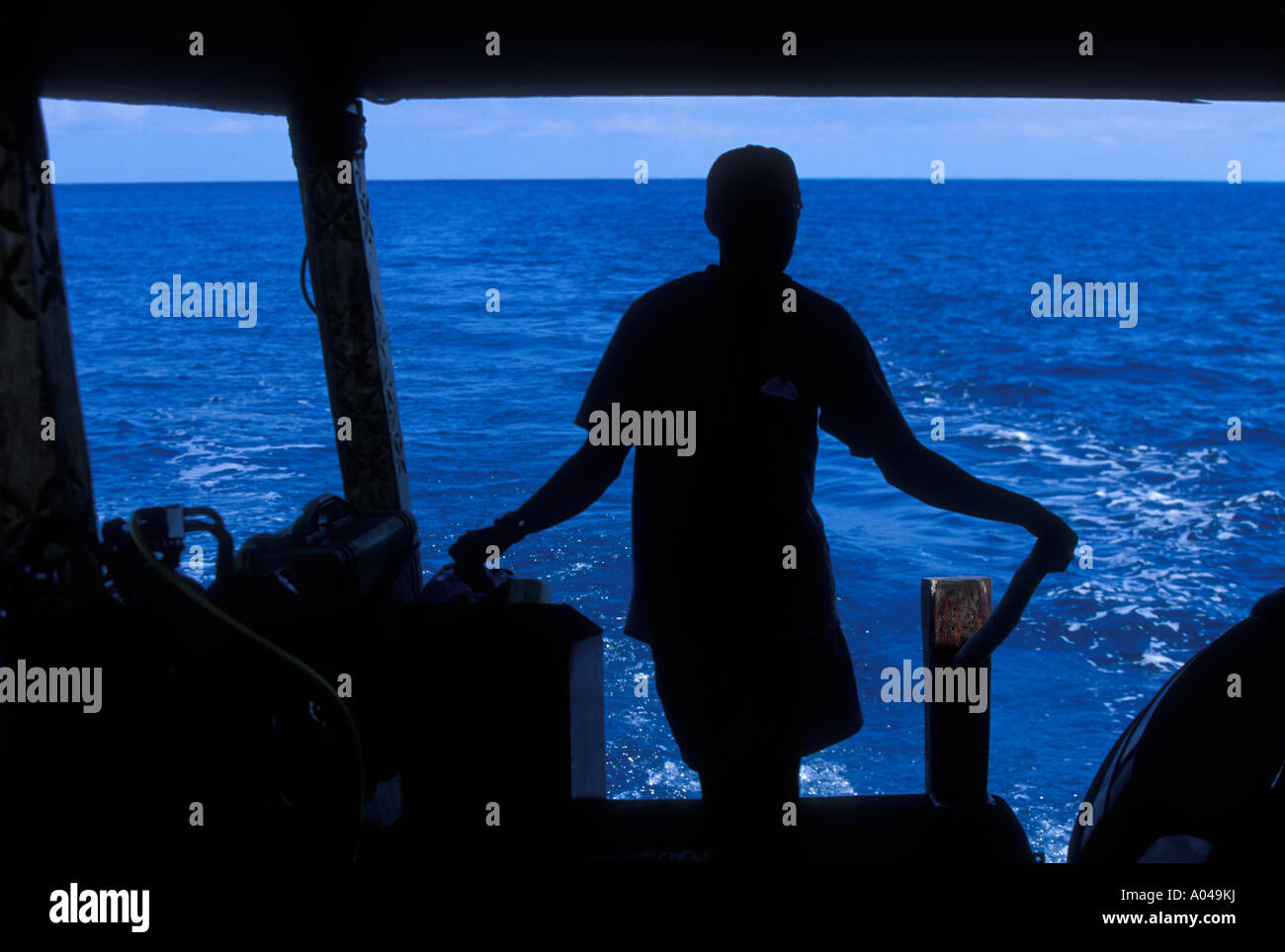 Africa Tanzania Zanzibar Matemwe Bay Silhouette of boat captain piloting charter boat on Indian