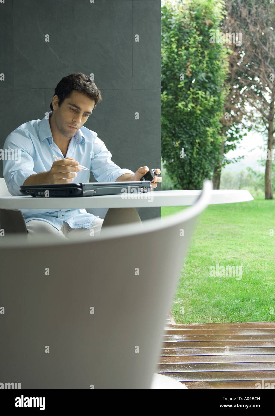 Man sitting at table outdoors, working Stock Photo