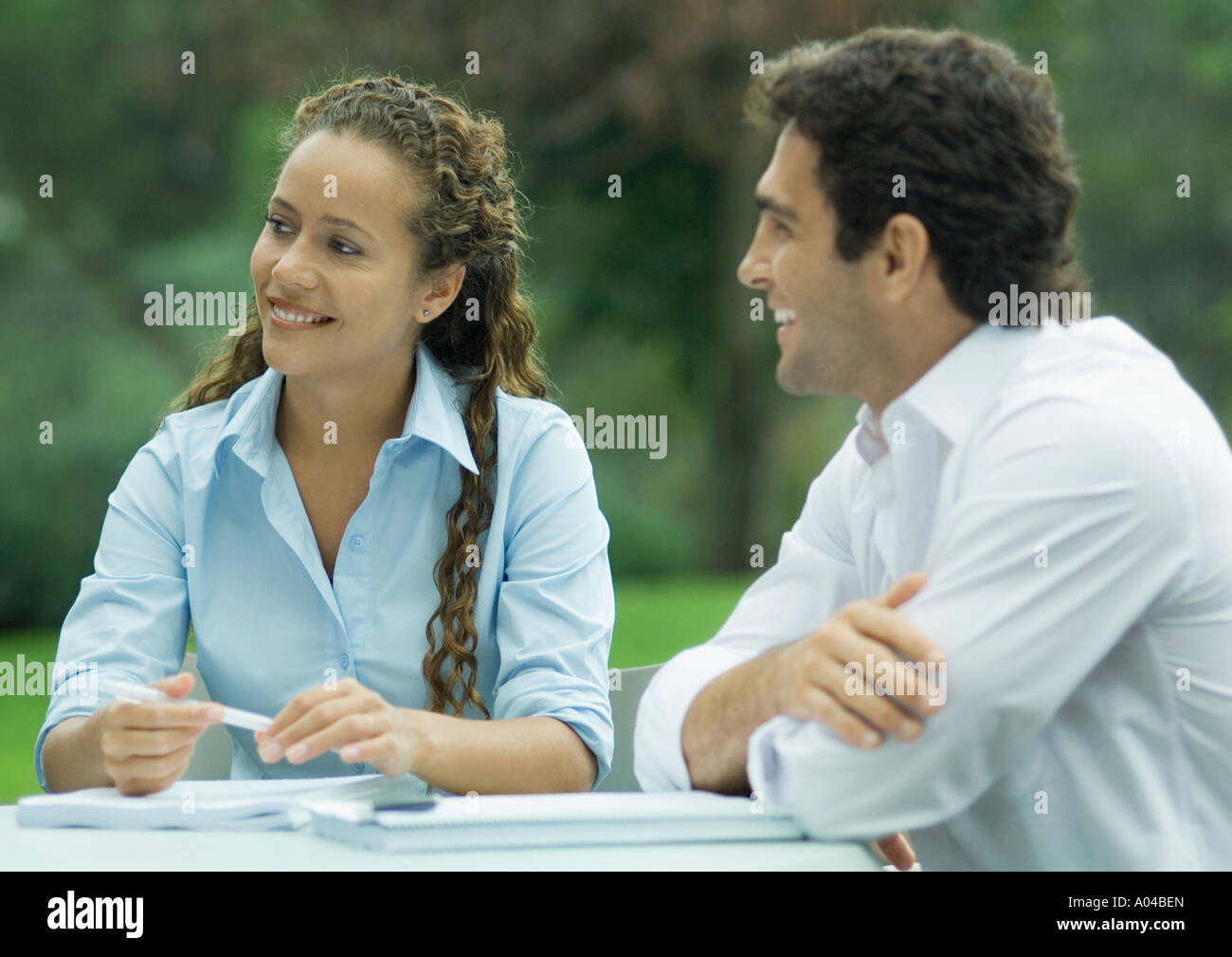 Woman and man, outdoors, sitting with documents and pen at table Stock Photo