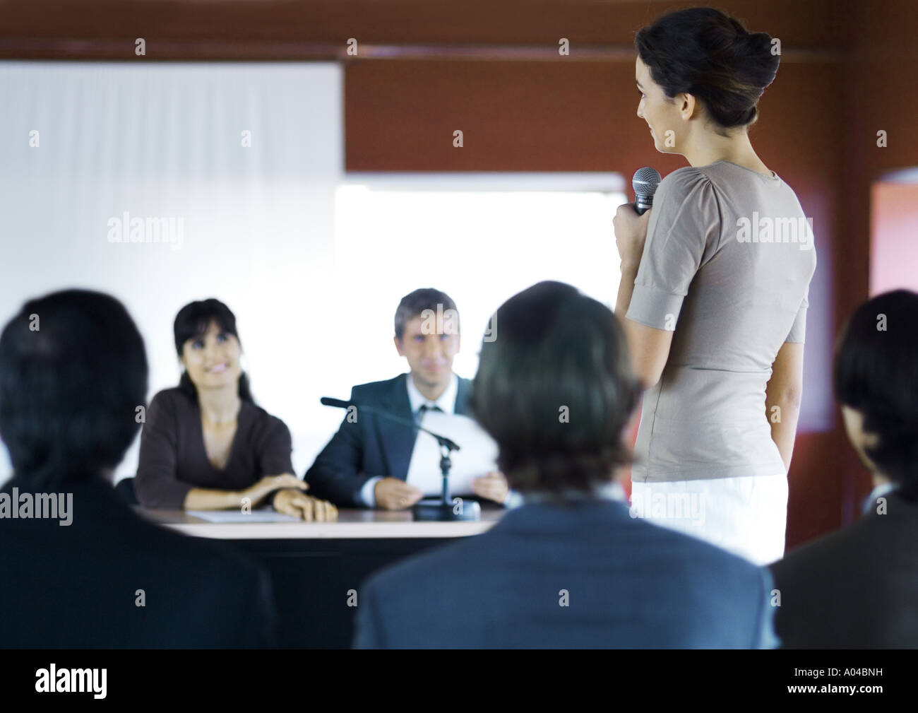 Businesspeople in seminar, one woman standing with microphone Stock Photo