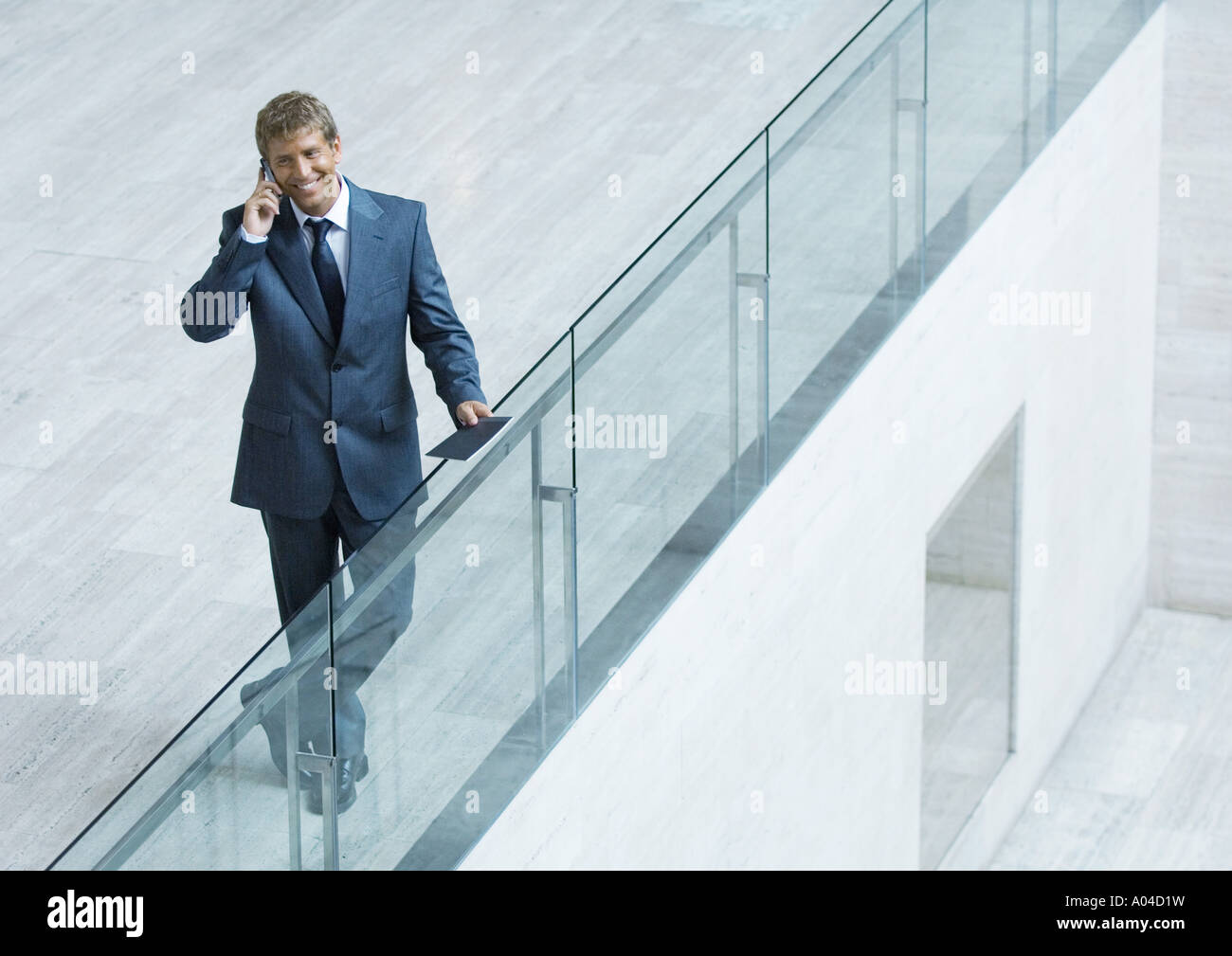 Businessman leaning on railing, using cell phone, high angle view Stock Photo