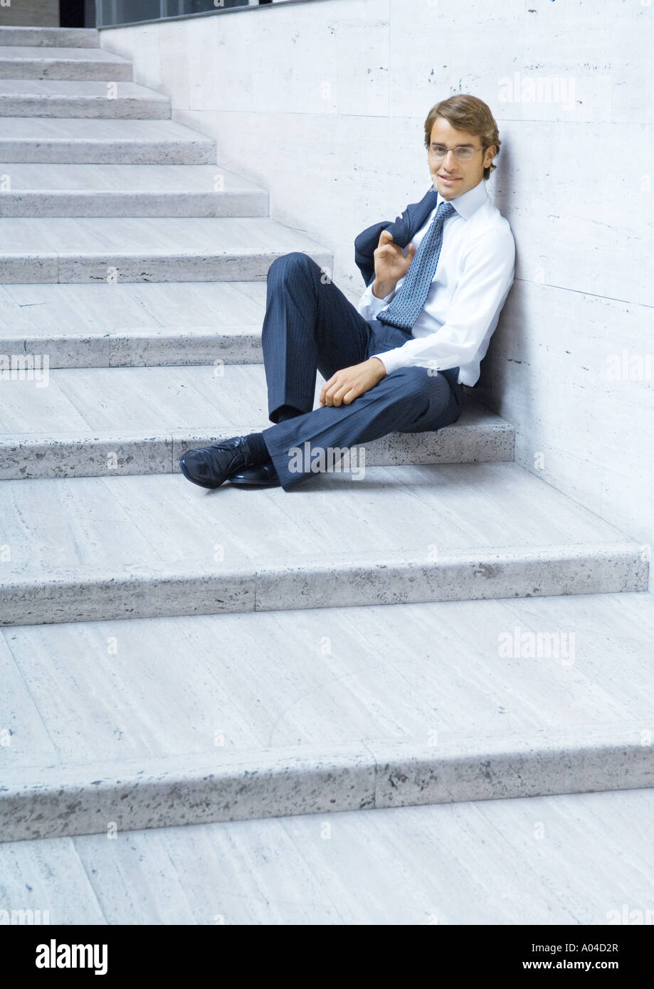 Businessman sitting on steps, smiling Stock Photo